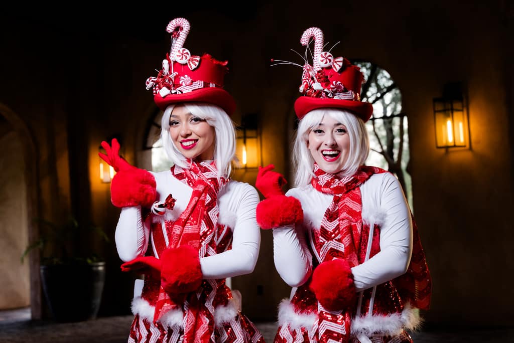 Two peppermint-striped performers pose under an archway