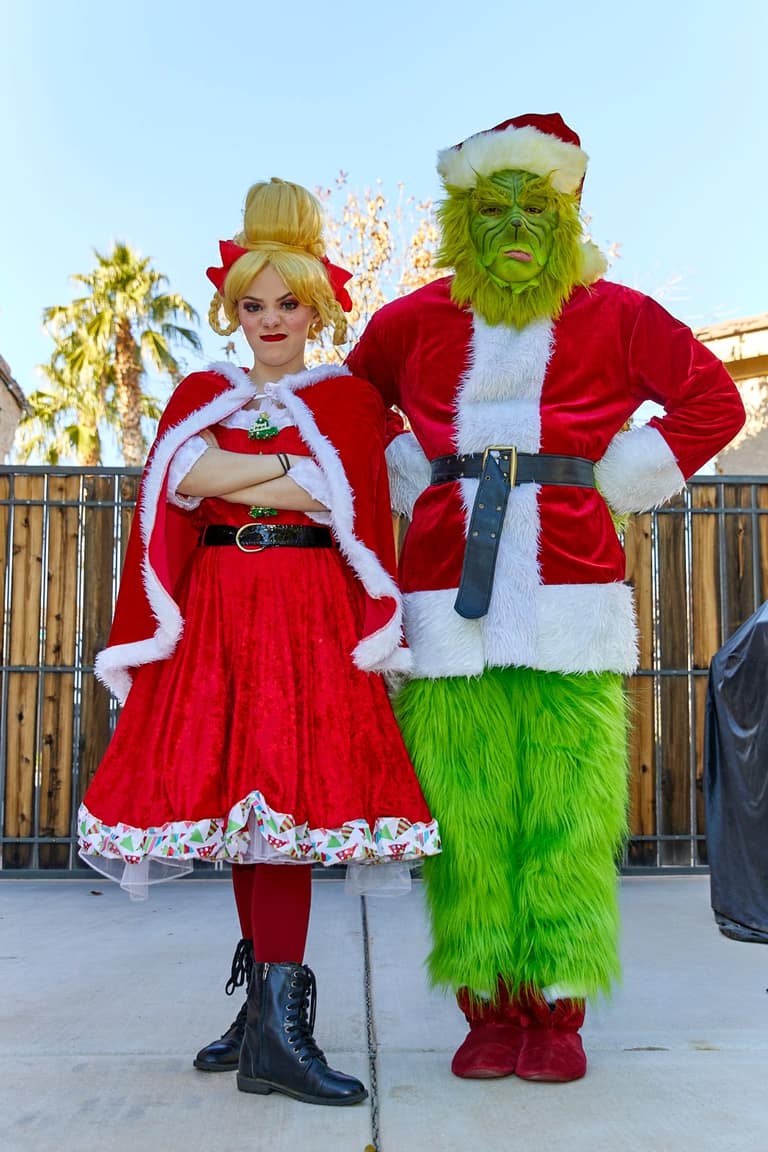 Cindy Lou Who and a Santa-suited Grinch character pose at a Christmas event