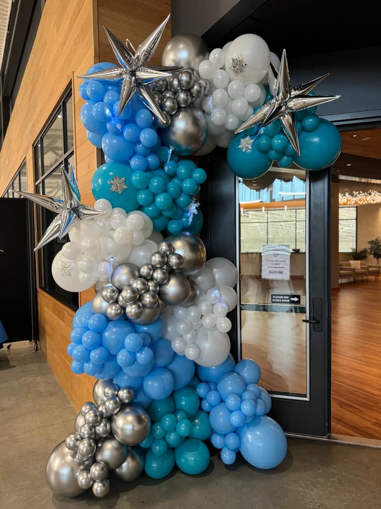 A blue, white, and silver balloon garland with star accents framing a doorway