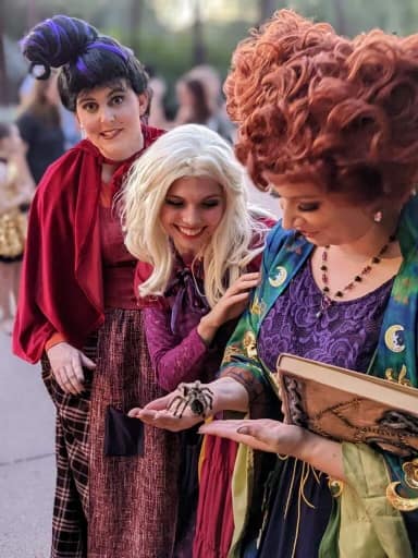 The three Sanderson sisters from Hocus Pocus at a Halloween gathering